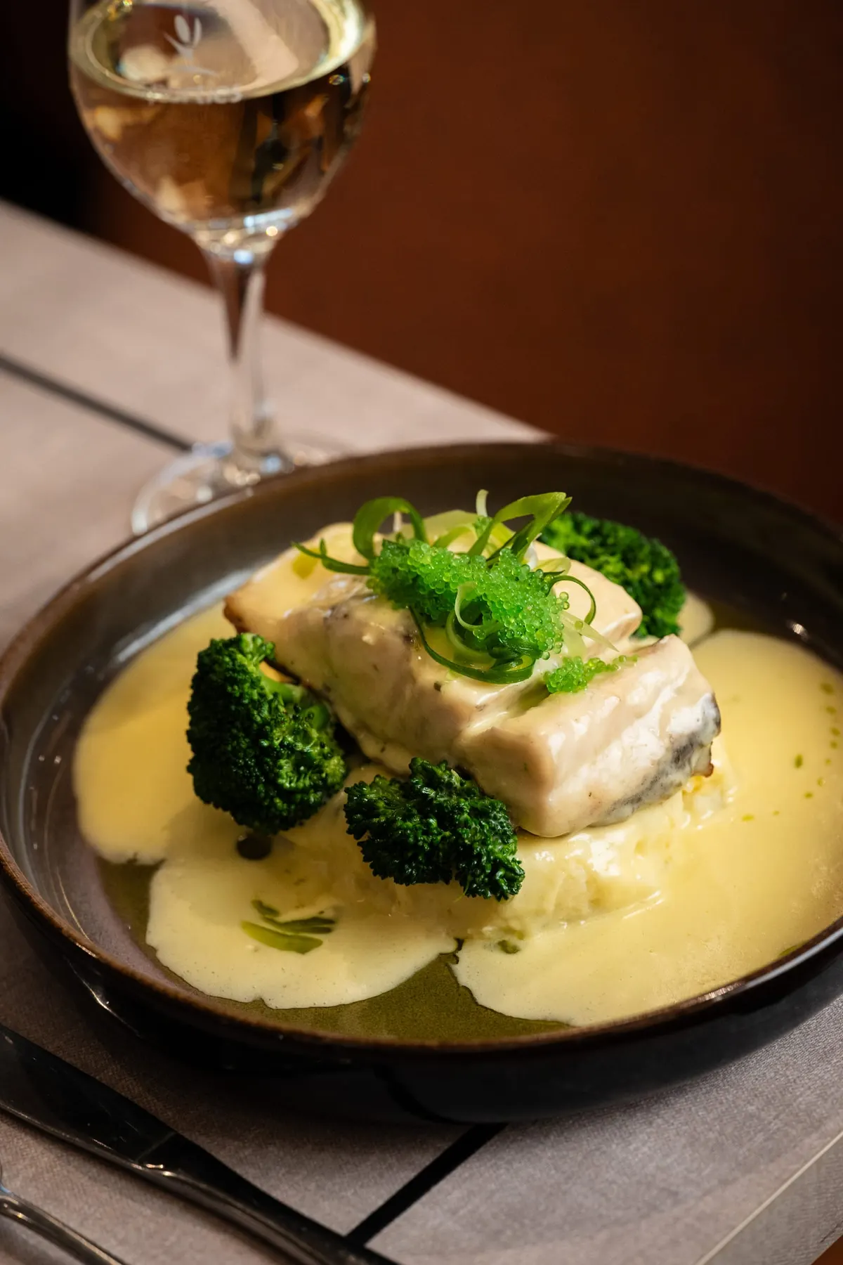 Grilled barramundi fillet on a creamy sauce with broccolini