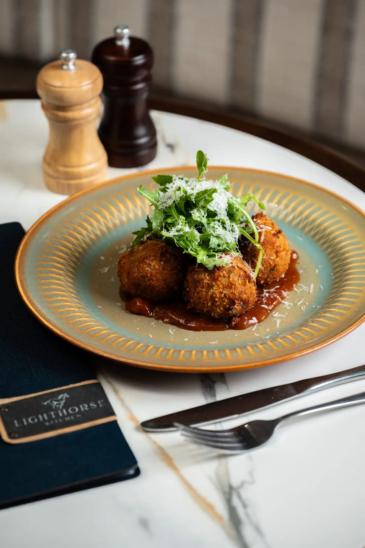 Arancini under rocket and shaved parmesan, on a rich sauce