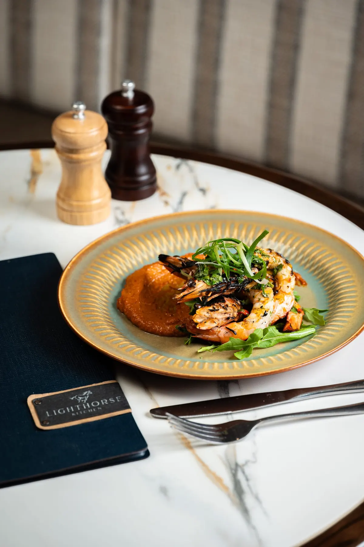 Crispy-skin fish with purée and leaves on a gold-rimmed plate