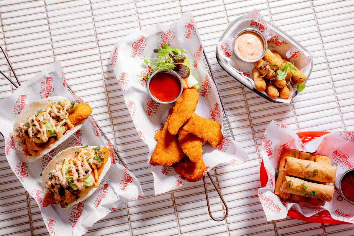 Diner spread of tacos, chicken strips and spring rolls from above
