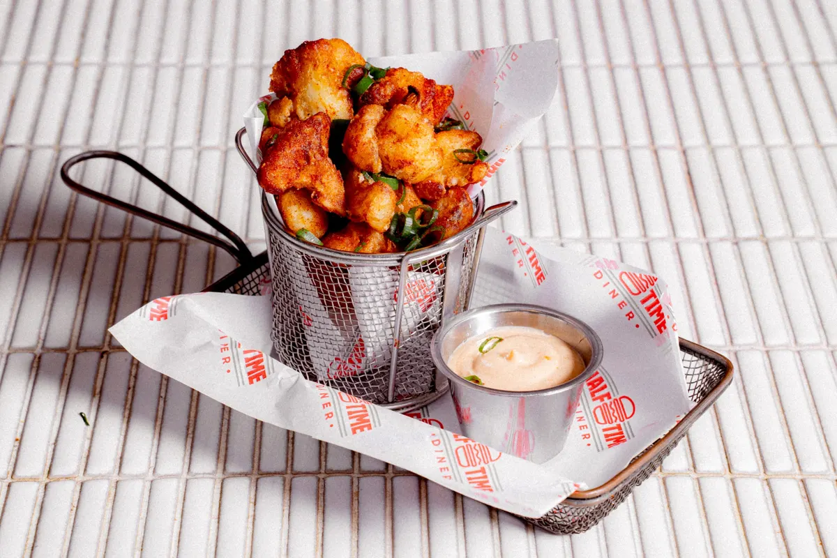 Crispy popcorn bites in a wire fry basket with aioli
